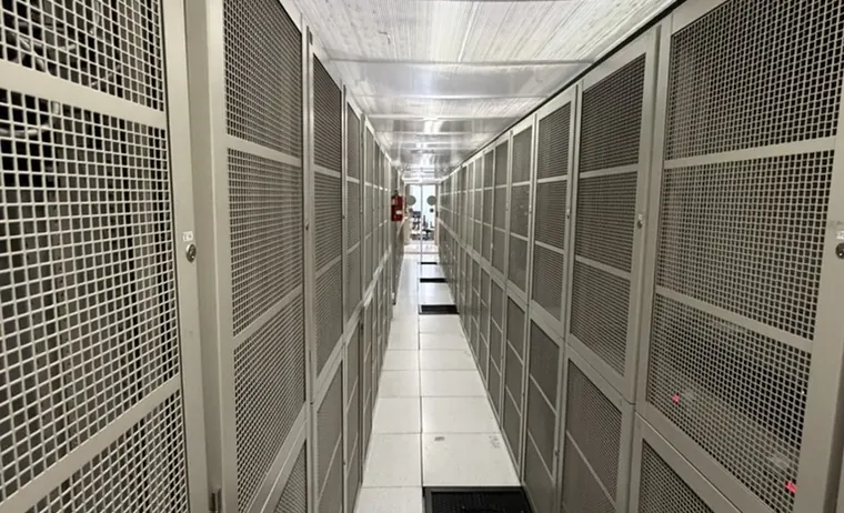 Pasillo técnico entre gabinetes mallados, con piso elevado y rejillas de ventilación