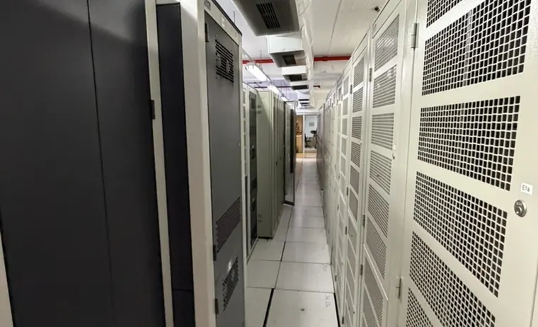 Corredor de la sala de datos con gabinetes cerrados y conductos de climatización sobre el pasillo